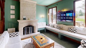 Ein Wohnzimmer mit Kamin, großem Fernsehbildschirm und einer Sitzecke.