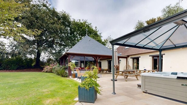 Ein Patio mit Whirlpool, Sitzgelegenheit im Freien und einer überdachten Struktur.