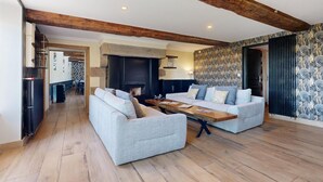 A spacious living area with a fireplace, two sofas, a wooden coffee table, and exposed wooden beams on the ceiling. - Auberge St Vincent Diligence 35 people 2 Cottage : jacuzzi games (Braffais – Le Parc)
