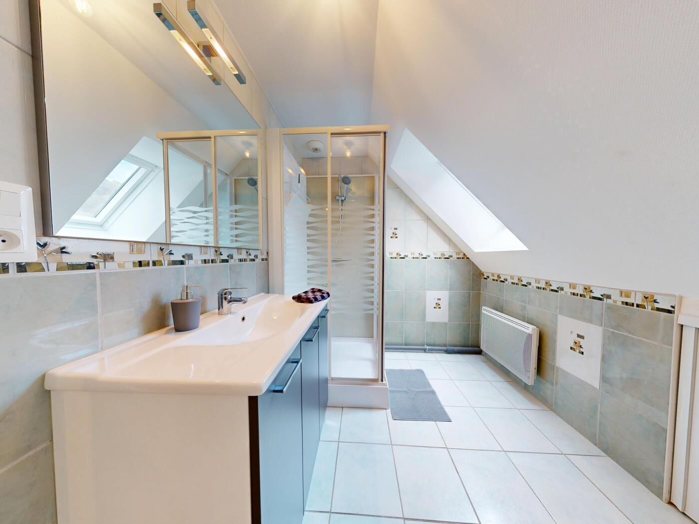 Un baño moderno con un espejo grande, un lavabo y una zona de ducha.