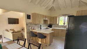 Une cuisine moderne dotée d’un îlot central, de meubles en bois et d’un réfrigérateur noir.