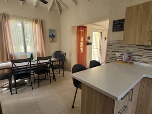 A modern kitchen with a large island, wooden cabinets, and a dining area with chairs and a table.