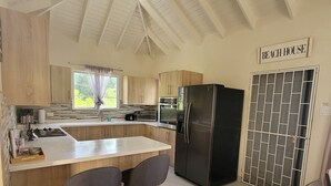 Une cuisine moderne avec des meubles en bois, un réfrigérateur noir et une pancarte indiquant « MAISON DE PLAGE ».