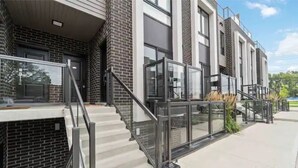 A modern building with a brick facade, large windows, and a staircase with glass railings. - Luxury New Condo By Niagara Falls (Niagara Falls)