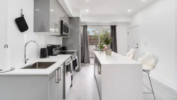 A modern kitchen with white cabinetry, stainless steel appliances, and a central island. - Luxury New Condo By Niagara Falls (Niagara Falls)