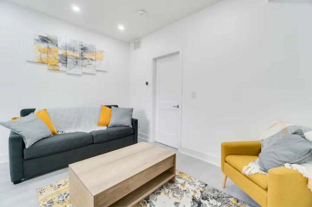 A modern living room with a dark grey sofa, a yellow armchair, and a wooden coffee table.