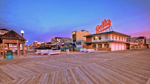 A boardwalk with buildings, including a diner with a neon sign.