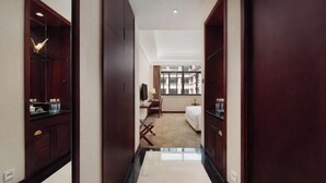 Un couloir d’hôtel avec un lit, un bureau et une chaise au fond.