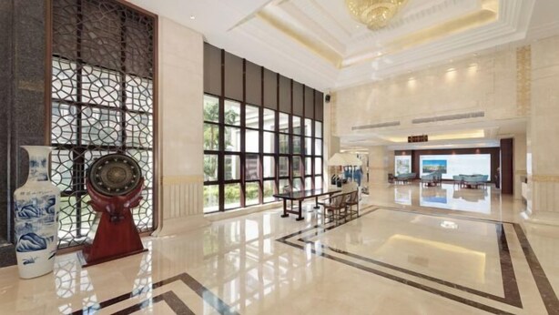 Un hall d’entrée spacieux, agrémenté d’un grand lustre, d’un paravent chinois traditionnel et d’un grand vase.