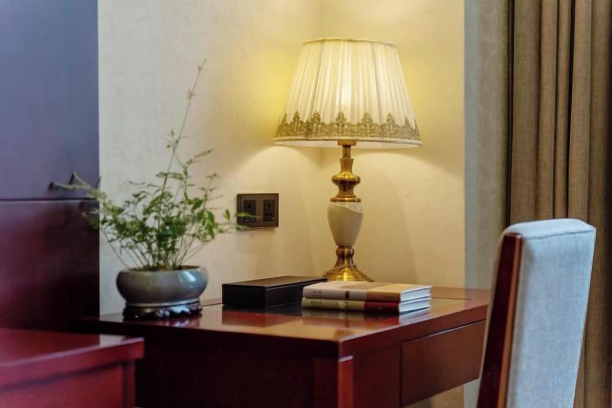 A wooden desk with a lamp, a book, and a potted plant.