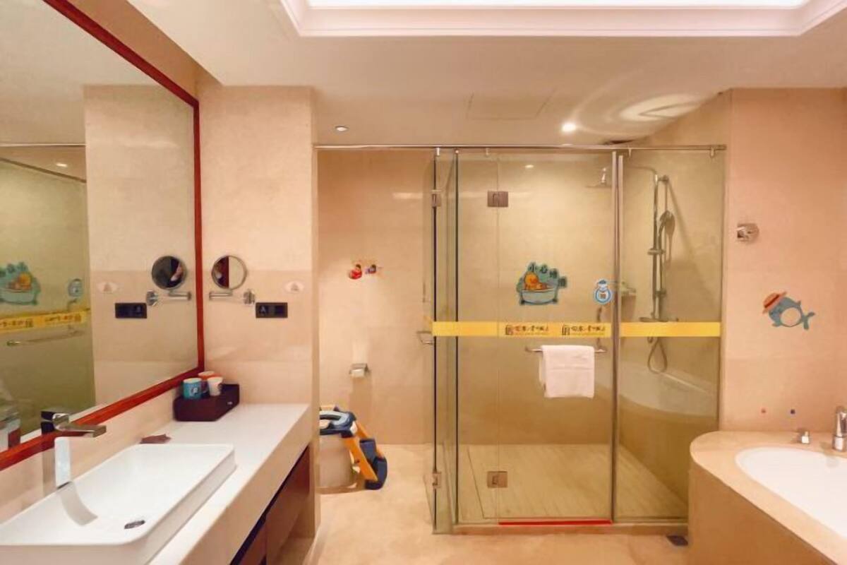 A modern bathroom with a glass-enclosed shower, a large mirror, and two sinks.