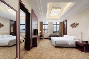 Quarto de hotel com duas camas, uma escrivaninha, uma cadeira, uma televisão e uma janela grande.