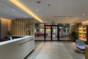 A reception area with a reception desk, a seating area with chairs, and a bookshelf. - Homeinn Hotel·neo(Xiushanmen Square Store, Qiupu West Road) (Chizhou)