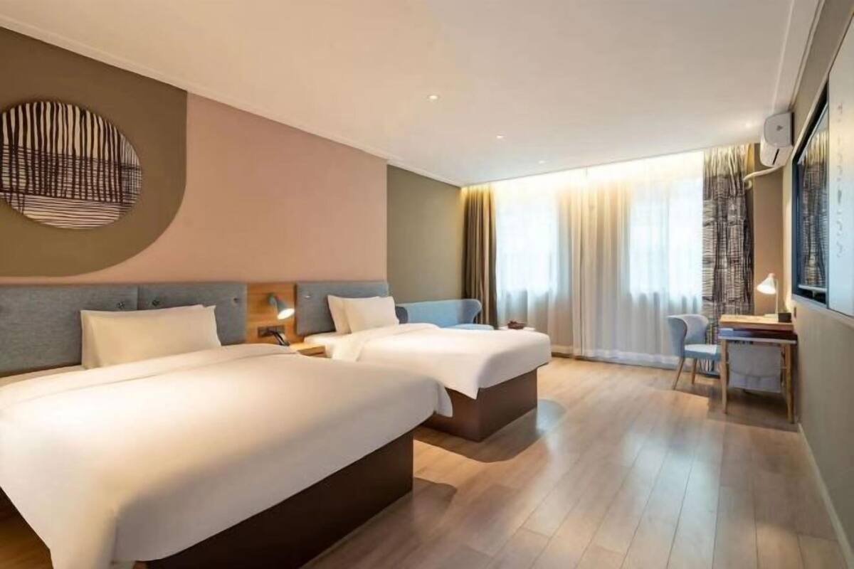 A hotel room with two beds, a desk, and a chair.