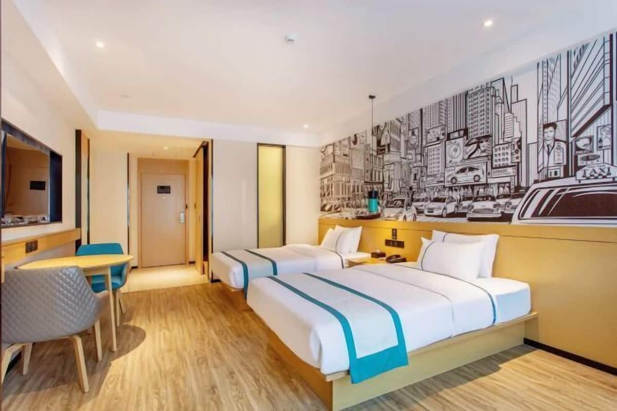 Habitación de hotel con dos camas, un escritorio y una silla.