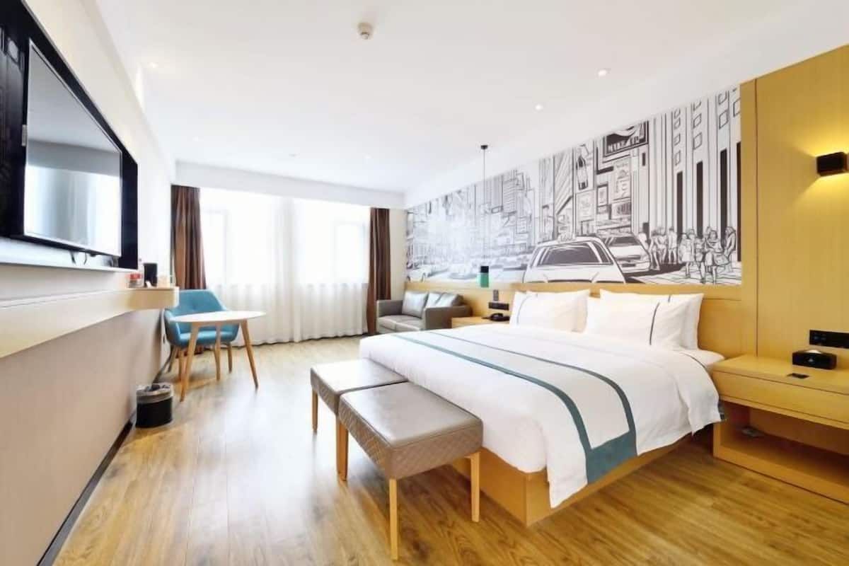 Una habitación de hotel con una cama grande, un escritorio, una silla y un mural en la pared.