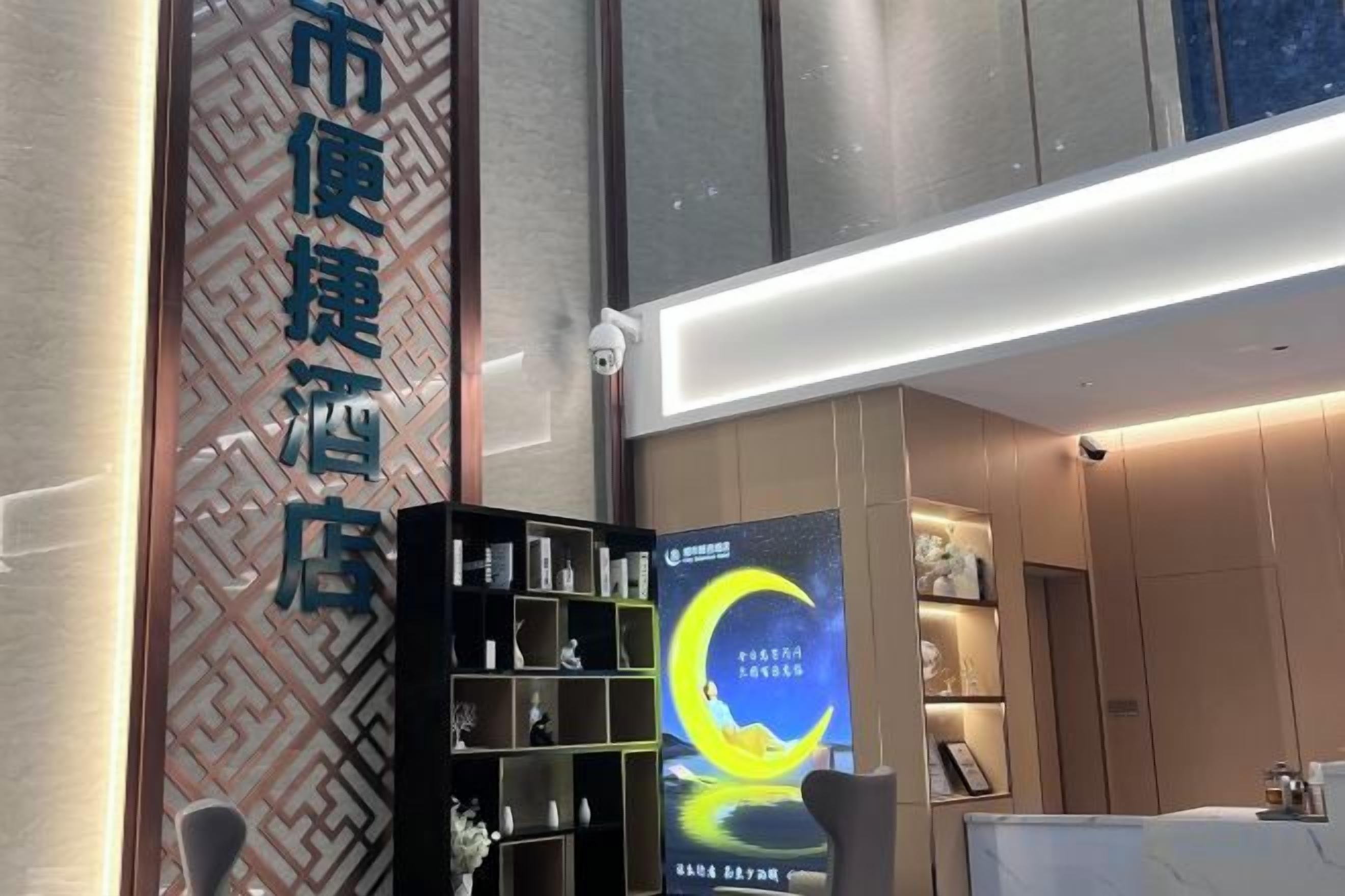 A hotel reception area with a modern design, including a reception desk, a digital display, and a wall-mounted sign.