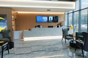 A hotel reception area with a reception desk, seating, a large window, and a television screen. - City Comfort Inn (Zhuji Xishi Theater Yongli Plaza) (Zhuji)