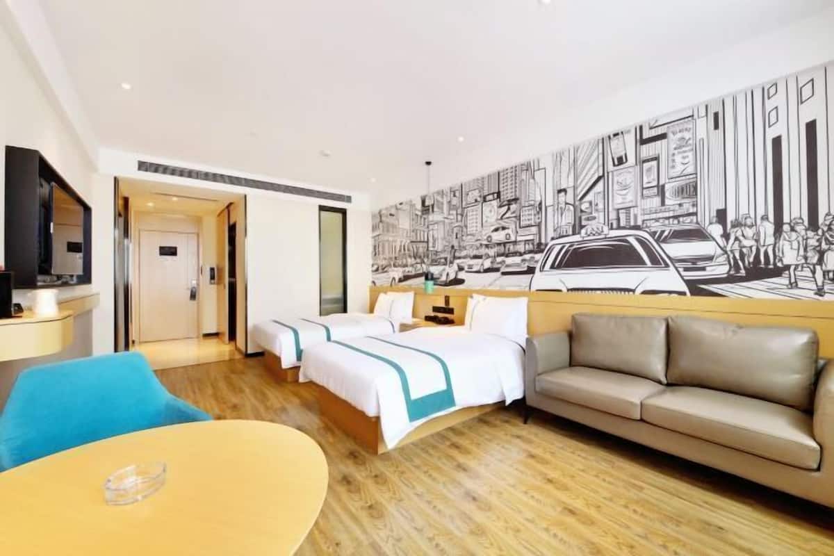 Una habitación de hotel con una cama, un sofá, un televisor y un mural en la pared.