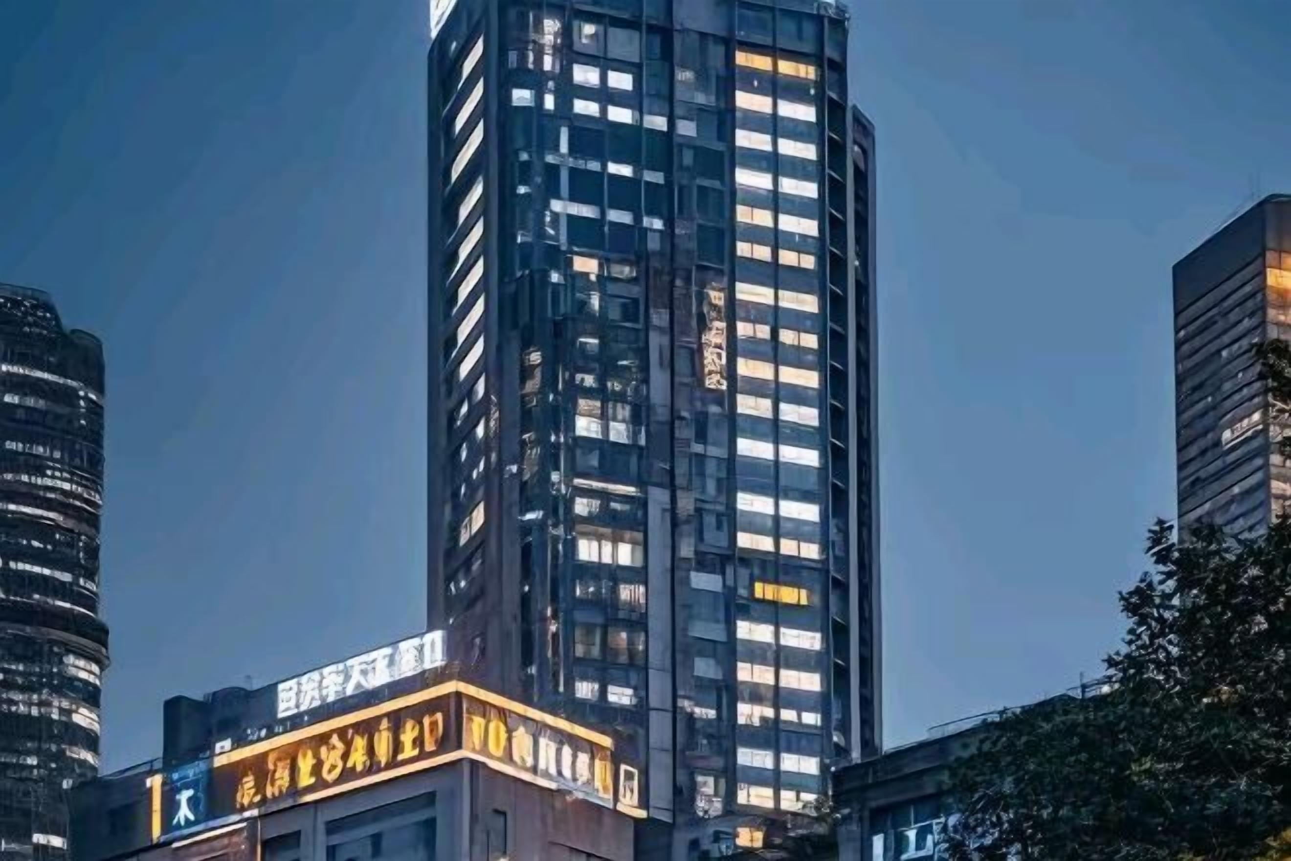 A high-rise building with illuminated windows and a sign with Chinese characters.