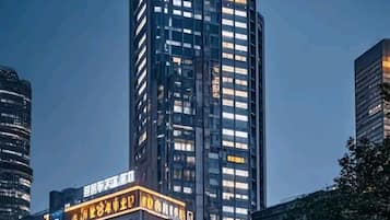 Un edificio alto con ventanas iluminadas y un letrero con caracteres chinos.