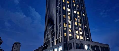 A high-rise building with multiple floors, large windows, and illuminated signage.