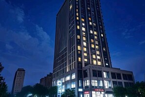 A high-rise building with multiple floors, large windows, and illuminated signage. - City Comfort Inn (Zhuji Xishi Theater Yongli Plaza) (Zhuji)