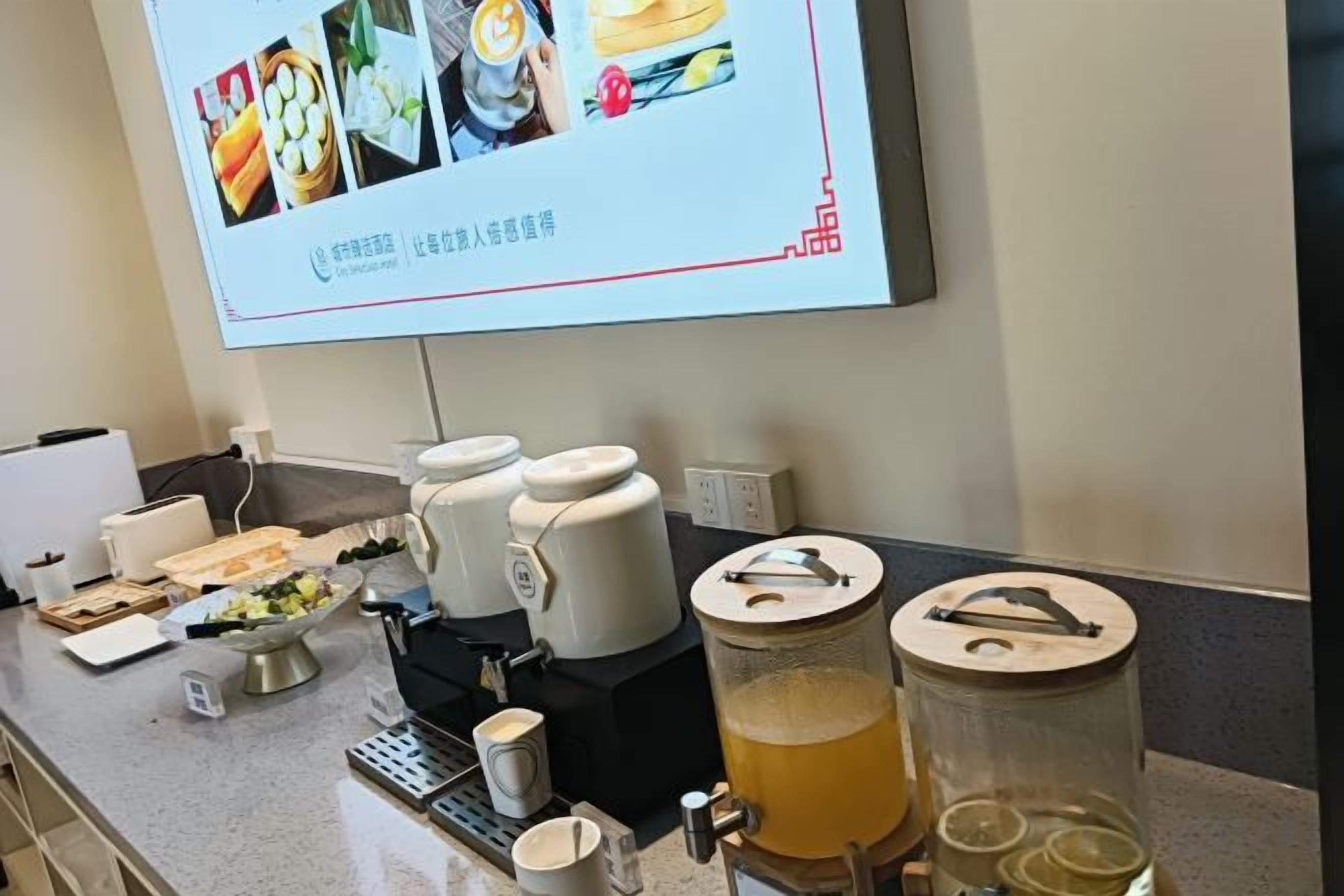 A breakfast bar with coffee makers, a tea kettle, and a juice dispenser.