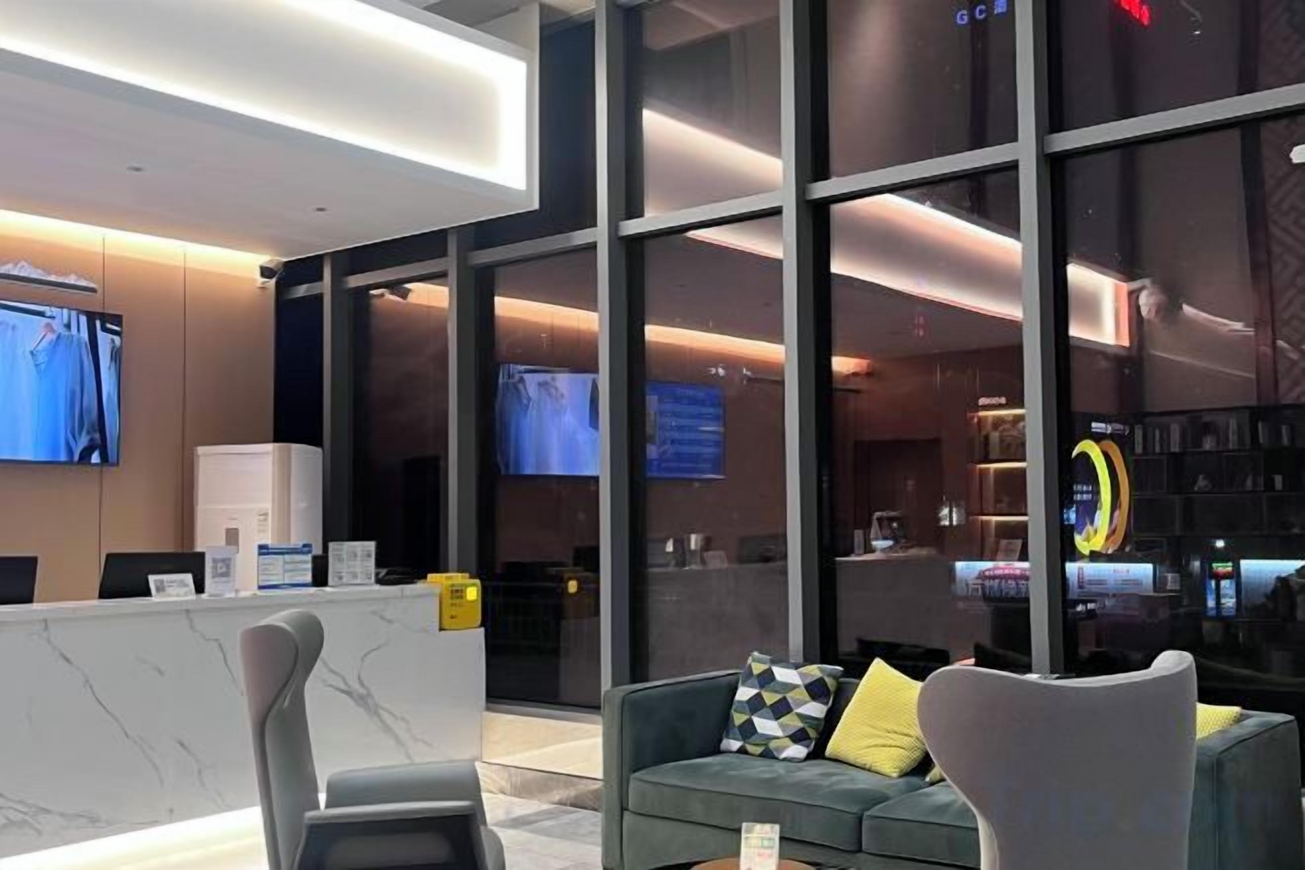 Un hall d’hôtel moderne avec un comptoir d’accueil, un espace salon et de grandes fenêtres.