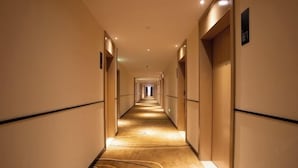 Un largo y estrecho pasillo de hotel con piso alfombrado y puertas a ambos lados.