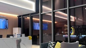 Un moderno vestíbulo de hotel con recepción, zona de estar y grandes ventanales.