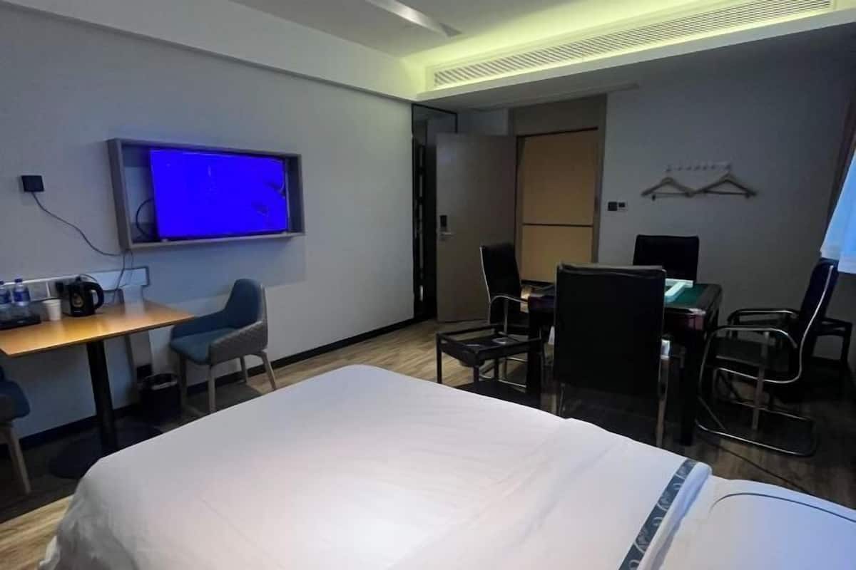 Una habitación de hotel con cama, escritorio, silla, televisor y armario.