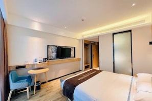 A hotel room with a bed, a desk, a chair, a television, and a wardrobe.