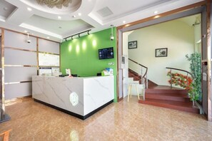 A reception area with a marble counter, a green wall with a digital screen, and a staircase leading to an upper floor. - Preferred Hotel (Shanghai Sheshan) (Shanghai)