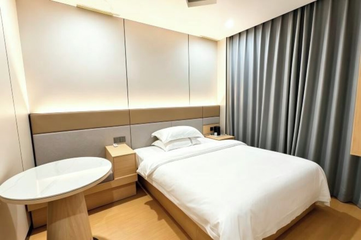 A hotel room with a bed, bedside table, and a small round table.