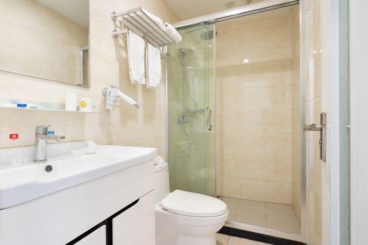 A bathroom with a glass shower enclosure, a white sink, and a toilet.
