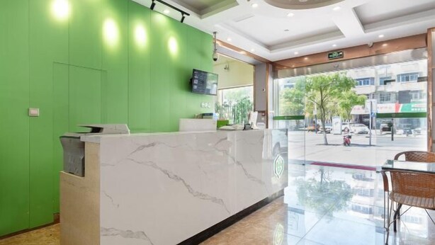 A reception area with a marble counter, green walls, a mounted TV, and a view of the street through large windows. - Preferred Hotel (Shanghai Sheshan) (Shanghai)
