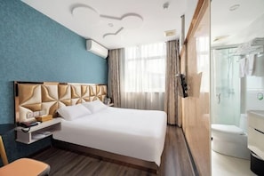 Habitación de hotel con cama, mesita de noche y zona de ducha.
