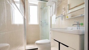 A bathroom with a glass shower enclosure, a white toilet, and a sink with a mirror above it. - Preferred Hotel (Shanghai Sheshan) (Shanghai)