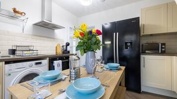 Una cocina moderna con una isla central, un refrigerador negro, un microondas y una lavadora.