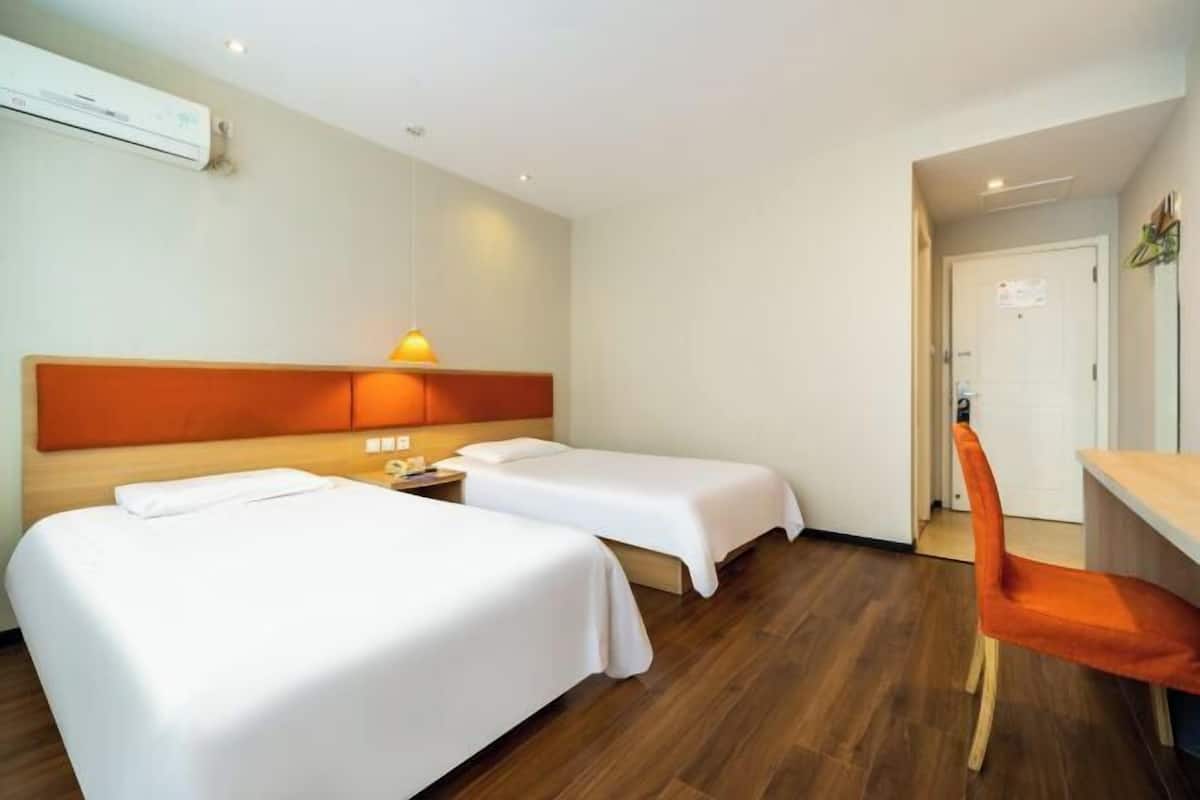 A hotel room with two beds, a desk, and a chair.