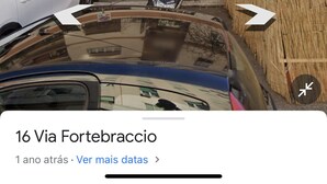 Ein mehrstöckiges Gebäude mit Balkonen, einem Ladenlokal und parkenden Autos.
