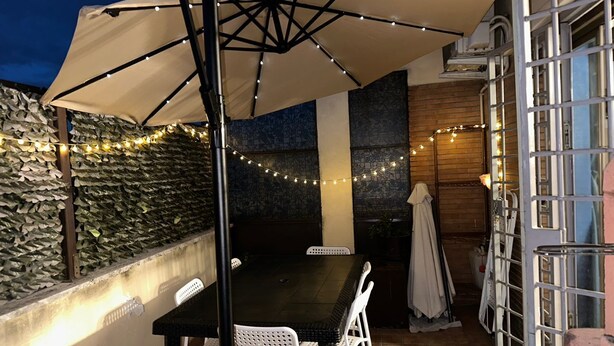 Eine Terrasse im Freien mit Tisch und Stühlen, Lichterketten und einem überdachten Bereich.