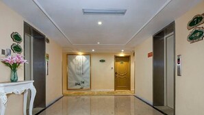 A hotel lobby with a marble floor, two elevators, a reception desk, and a decorative wall. - Vienna 3 Best Hotel (inan Changqing University Town) (Jinan)