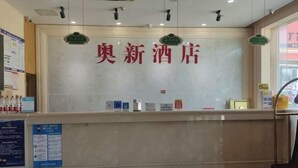 Una recepción con un cartel que dice '奥新酒店' y un mostrador con varios objetos.