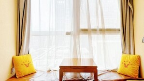 Una habitación con una cama, una mesa de madera y almohadas amarillas.