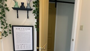 A restroom with a word list on the wall, a small plant, and a radiator. - Fairytale Forest River Cabin (Caledonia)