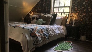 A cozy bedroom with a bed, pillows, a blanket, a small rug, and a nightstand. - Fairytale Forest River Cabin (Caledonia)