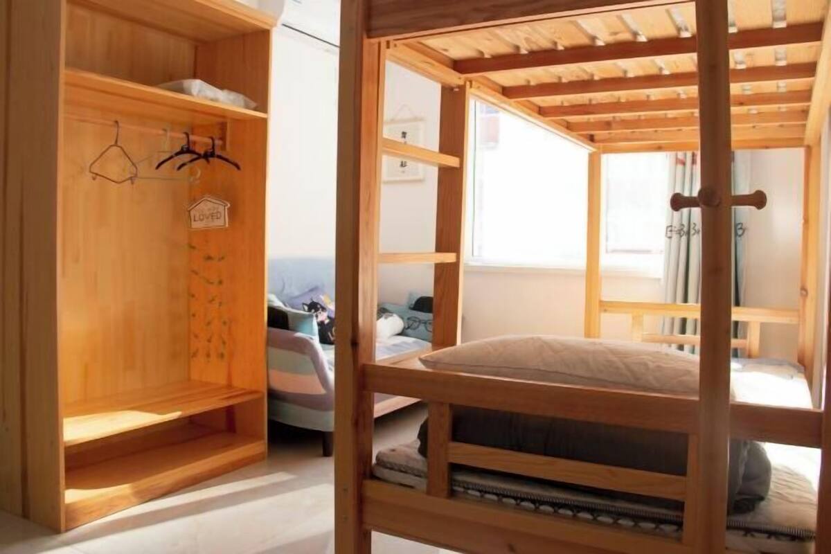 Une chambre avec un lit superposé, une armoire en bois et une fenêtre avec des rideaux.