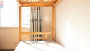 A room with a bunk bed, a window with curtains, and a bed with a patterned bedspread. - Shenyang Chang Kuan Gao Hostel (Shenyang)